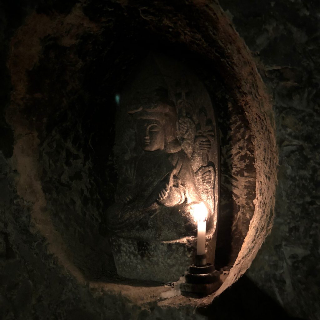 Candles light up this small statue of Benzaiten.