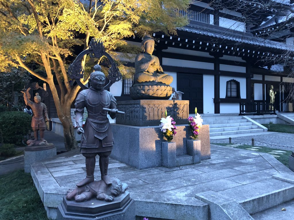 A statue of the historical Buddha surrounded by statues of guardian deities.