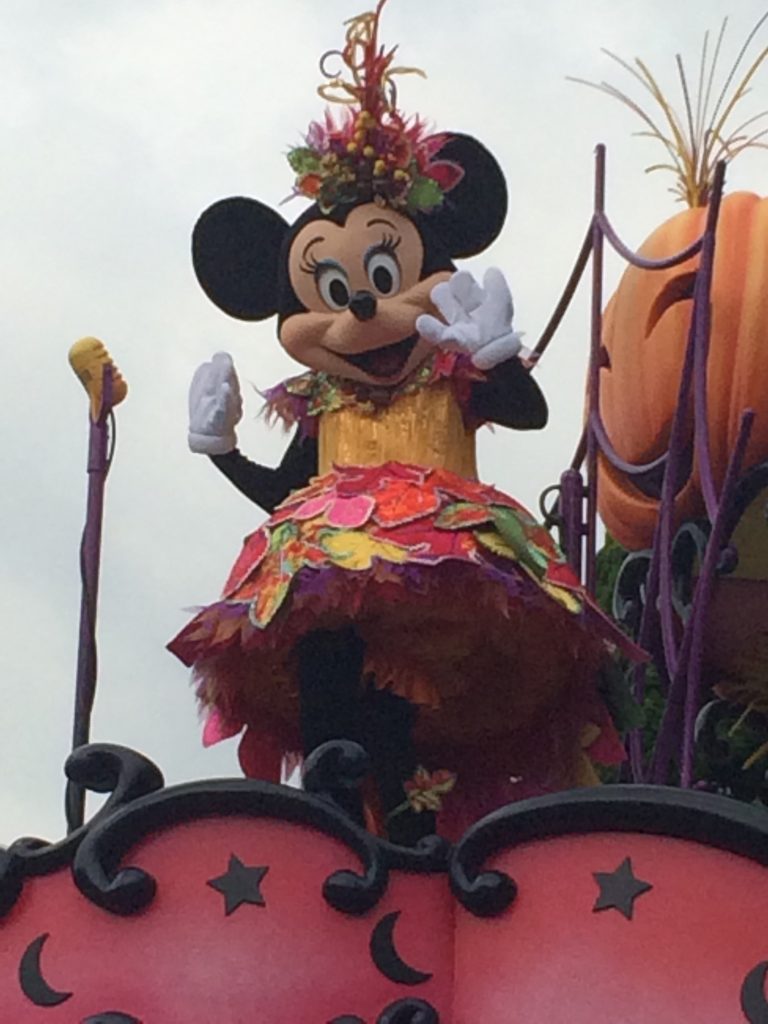 Minnie in a very cute harvest-themed dress, waving to the crowd.