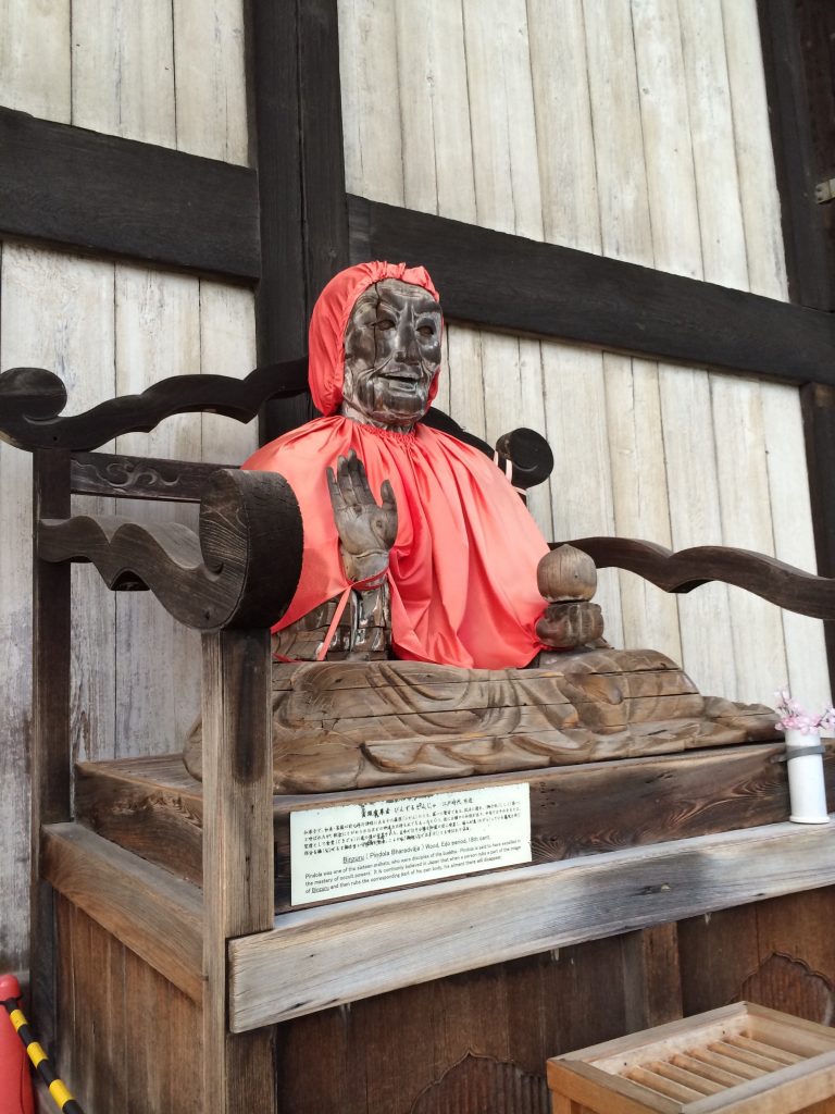 A dilapidated wooden statue wearing a red cloak.