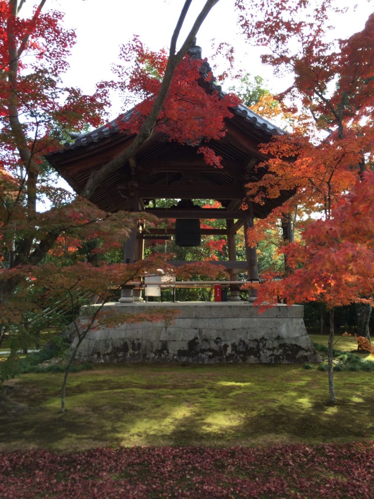 A small bell tower surrounded by red leaves.