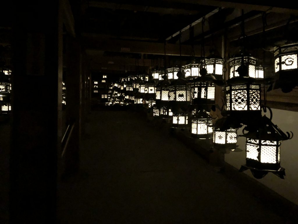 A room full of lit hanging lanterns and mirrors.