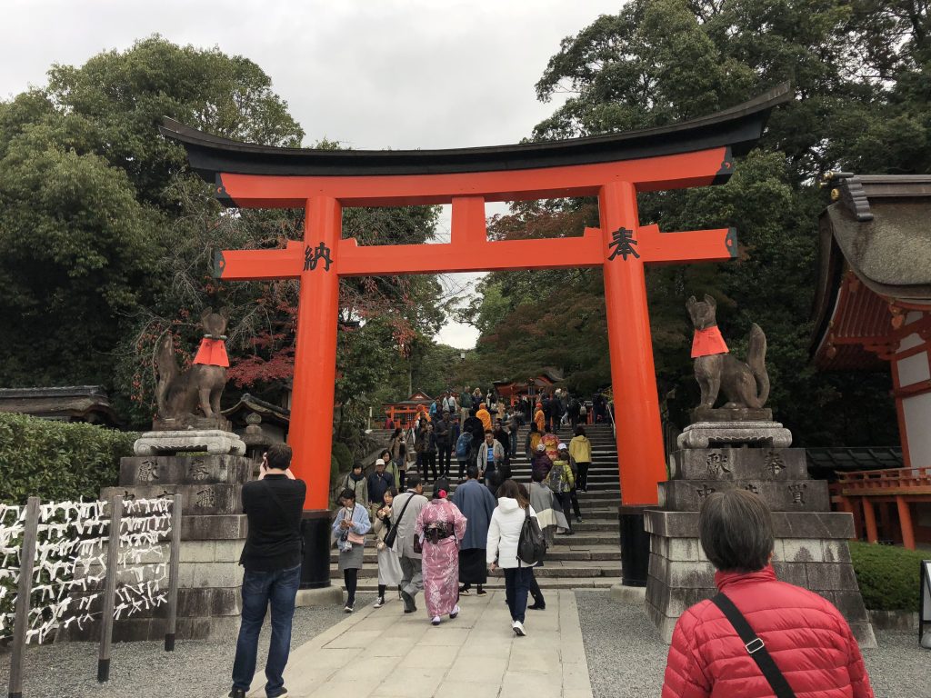 A large red torii surrounded on both sides by stone foxes.