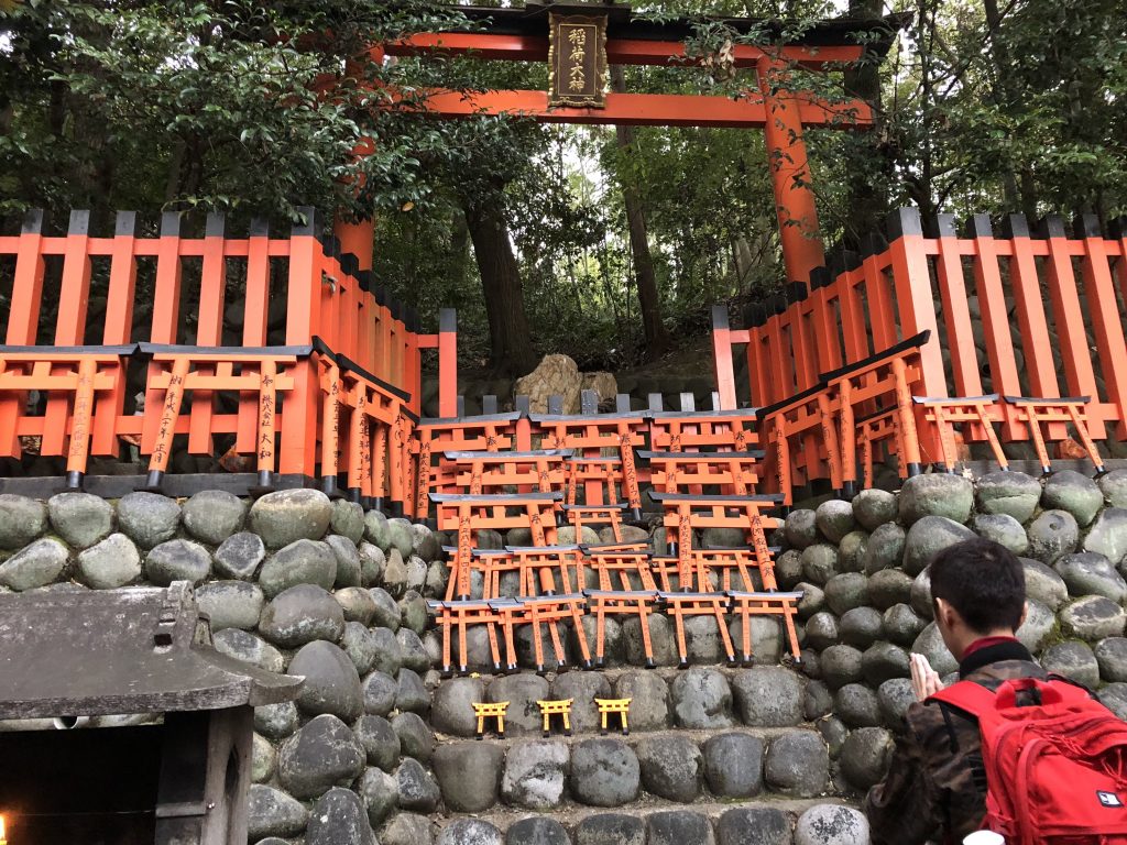 A large torii with a stone altar containing a few dozen tiny torii.