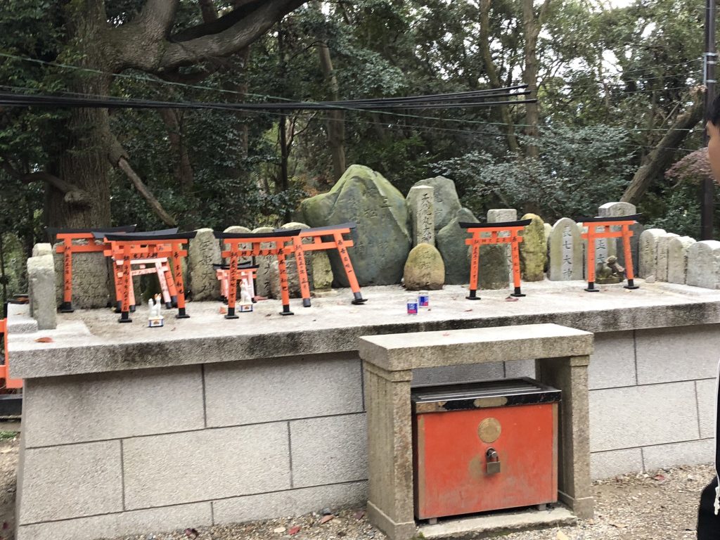 A smaller altar that contains more torii but also small fox statues and cups of sake.